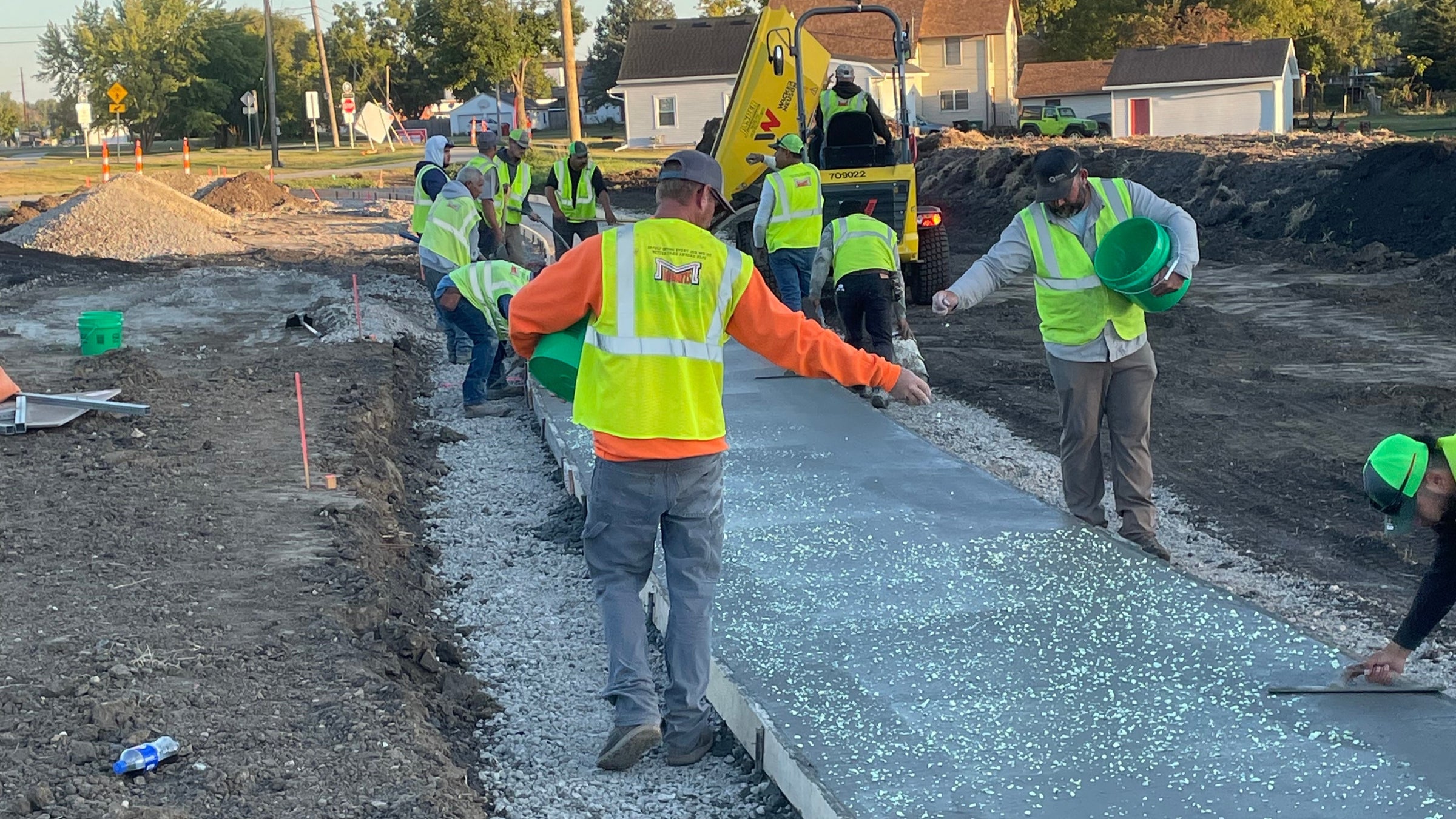 Workers in high-visibility vests laying asphalt on a road.